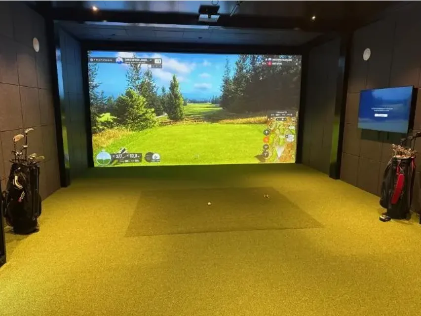 Golfsimulator-modul innvendig — svarte vegger, høyt tak, simulator klar til bruk